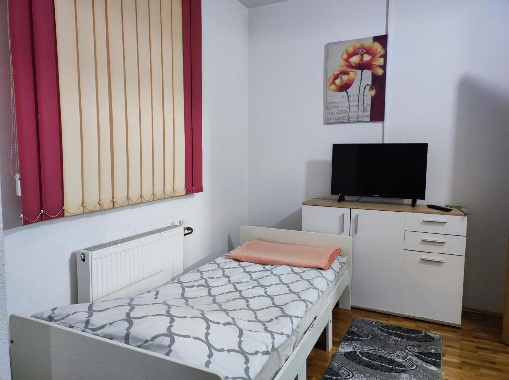 małą sypialnię z łóżkiem i telewizorem w obiekcie Vela-edo w mieście Zavidovići
