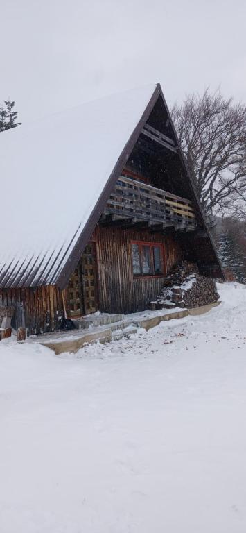 a large wooden barn in a snow covered field at Samostanska kuća in Fojnica