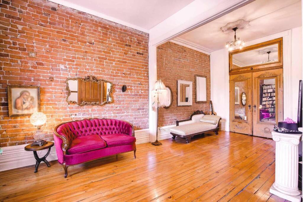 a living room with a pink couch and a brick wall at Plateau Mt-R à 2 pas des métros Laurier & Rosemont in Montreal