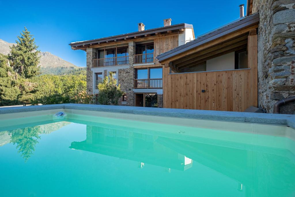 a swimming pool in front of a house at Chalet l'ozio creativo in Castelnuovo Nigra