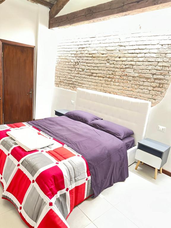 a bedroom with a bed and a brick wall at Venice Rainbow apartments San Zaccaria in Venice
