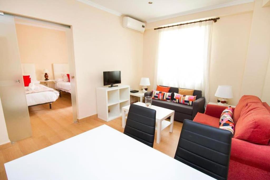 a living room with a red couch and a bed at Piso junto a la Catedral, 4-5 personas in Málaga