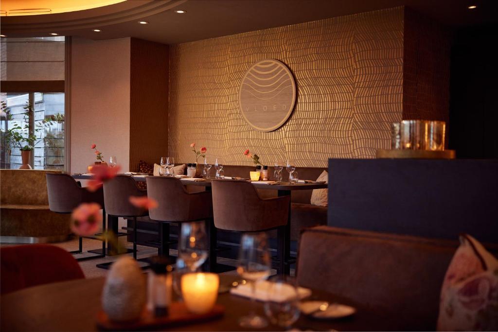 a restaurant with tables and chairs and a wall at Van der Valk Palace Hotel Noordwijk in Noordwijk aan Zee