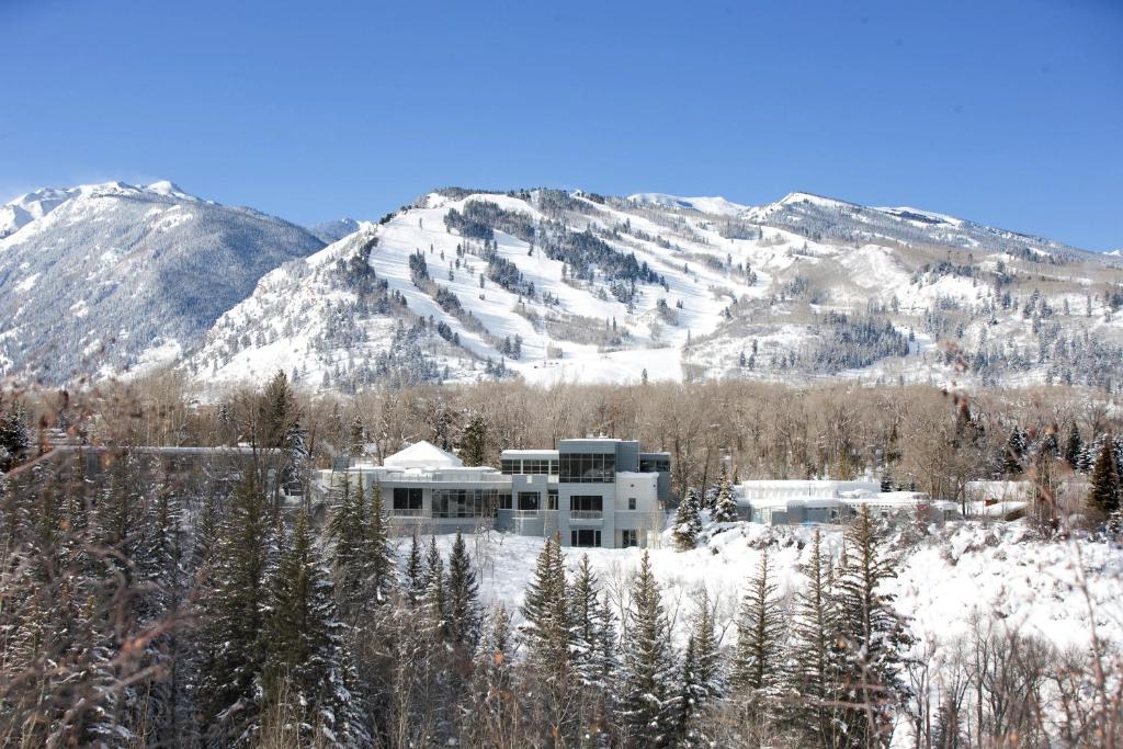 a building in the snow with mountains in the background at Aspen Meadows Resort in Aspen