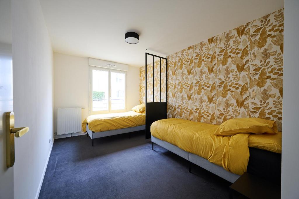 een slaapkamer met 2 bedden met gele lakens en een muur bij YELLOW House - Terrasse - Proche Paris et transports - Tout équipé in Montfermeil