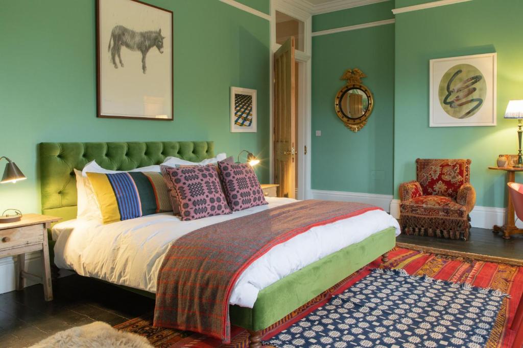 Un dormitorio con una cama con almohadas de colores y una silla. en The West End - Hawarden Castle en Hawarden