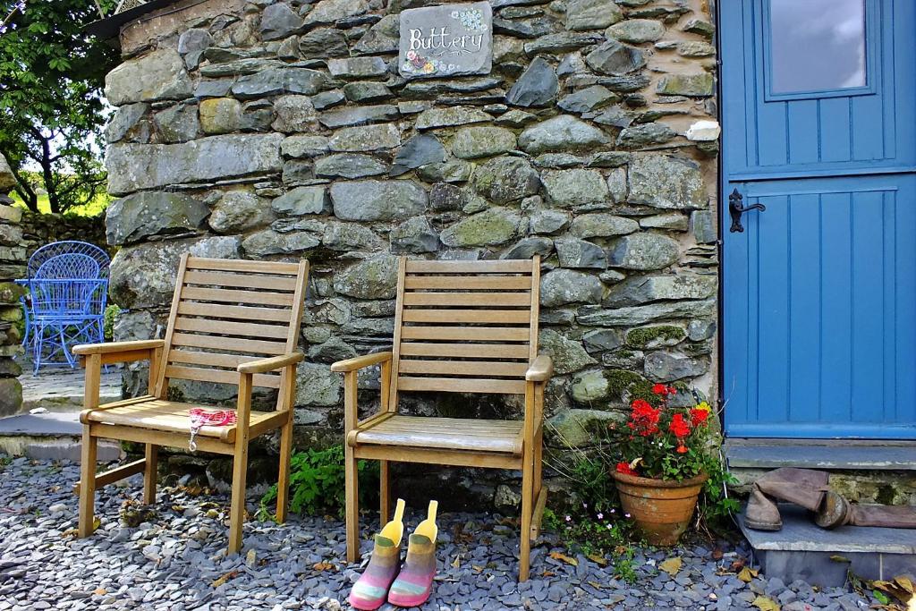 dos sillas y zapatos sentados junto a una pared de piedra en Finest Retreats - Woodend - The Buttery, en Ulpha