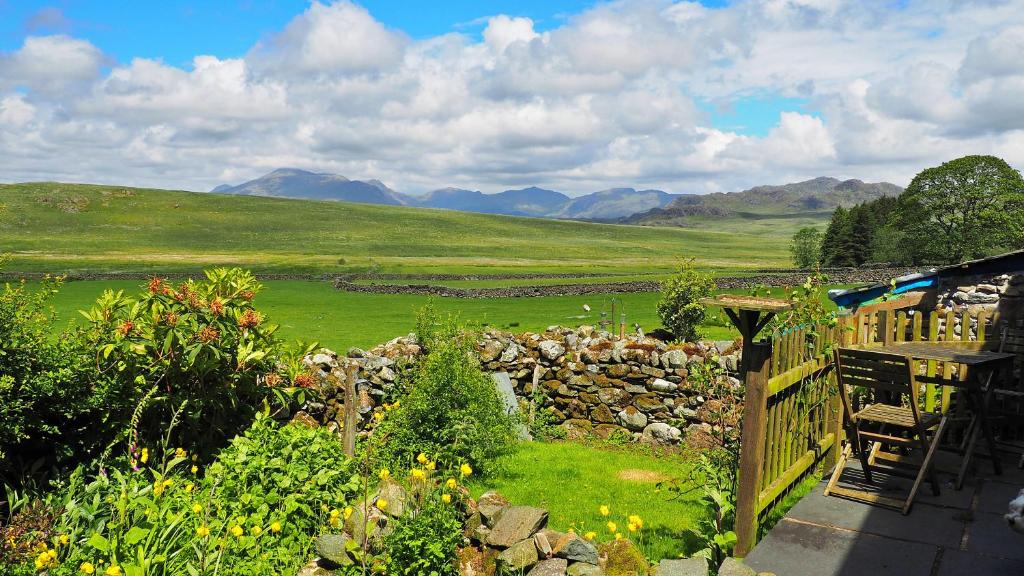 a garden with a stone fence and mountains in the background at Finest Retreats - Woodend - The Cottage in Ulpha