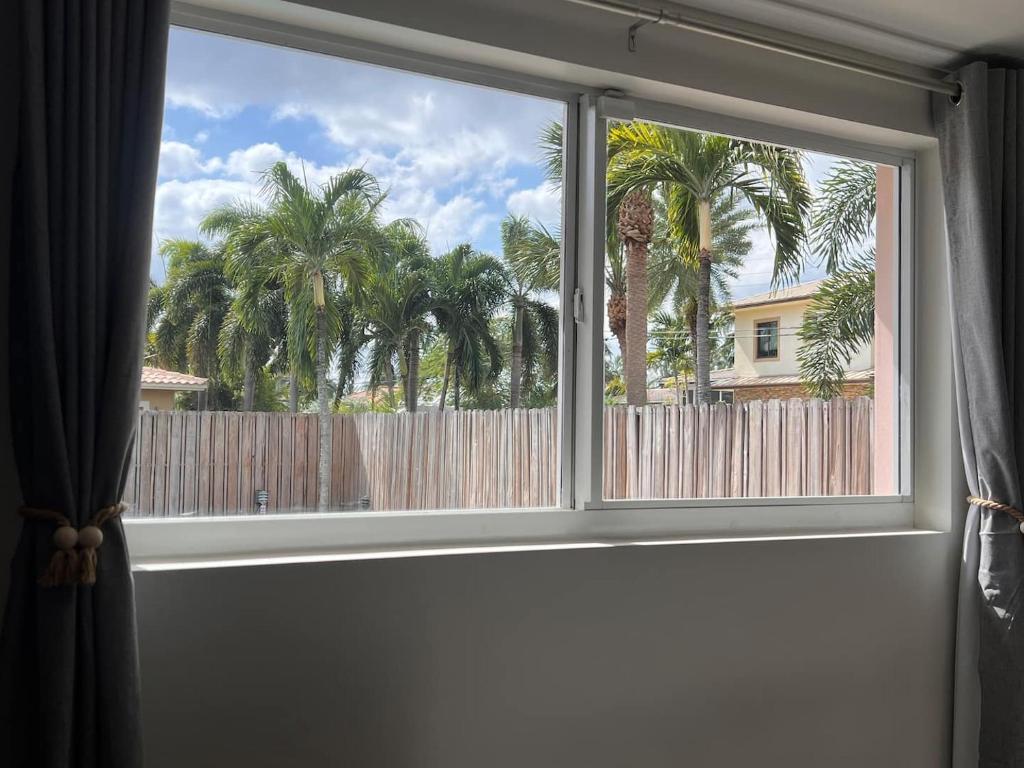 a window with a view of a fence and palm trees at Carlton Guest house in Fort Lauderdale