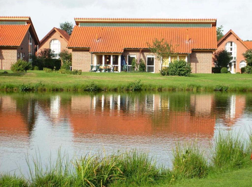 een huis met een oranje dak naast een meer bij Ferienhaus Gut Düneburg in Haren