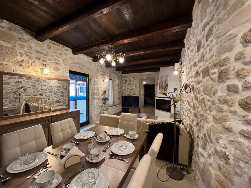 een eetkamer met een tafel en een stenen muur bij Pyrgou Villa Spacious and Unique 1 in Pirgoú