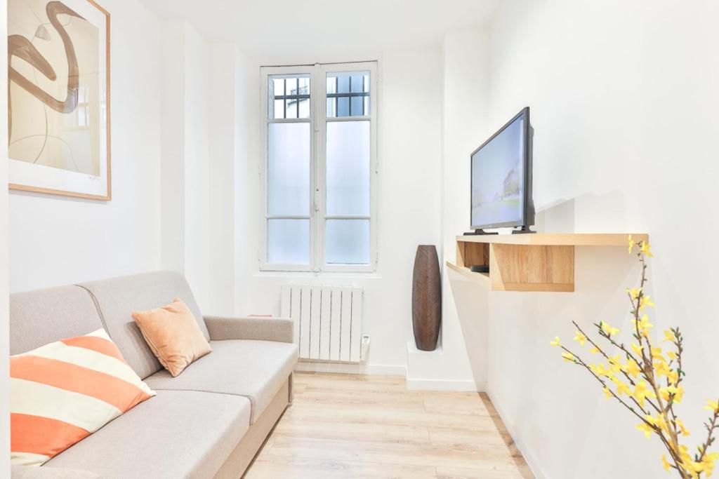 un salon blanc avec un canapé et une télévision dans l'établissement Charming studio - 2P - Eiffel Tower, à Paris