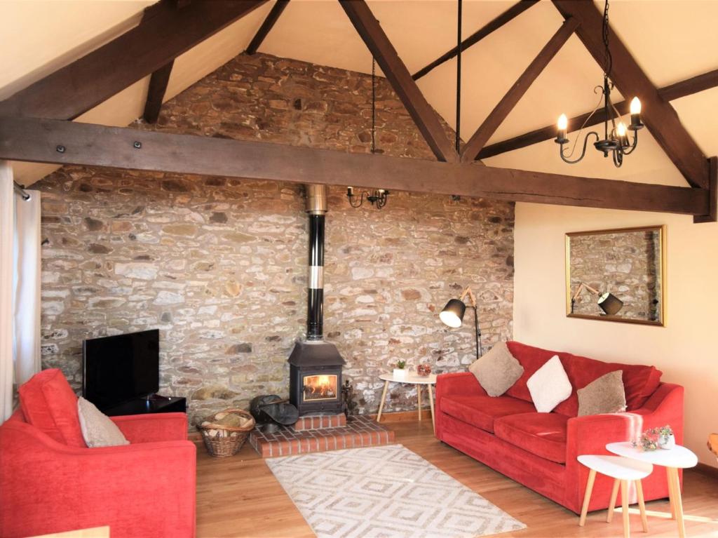 a living room with a red couch and a fireplace at 1 Bed in Bude WBARN in Sutcombe