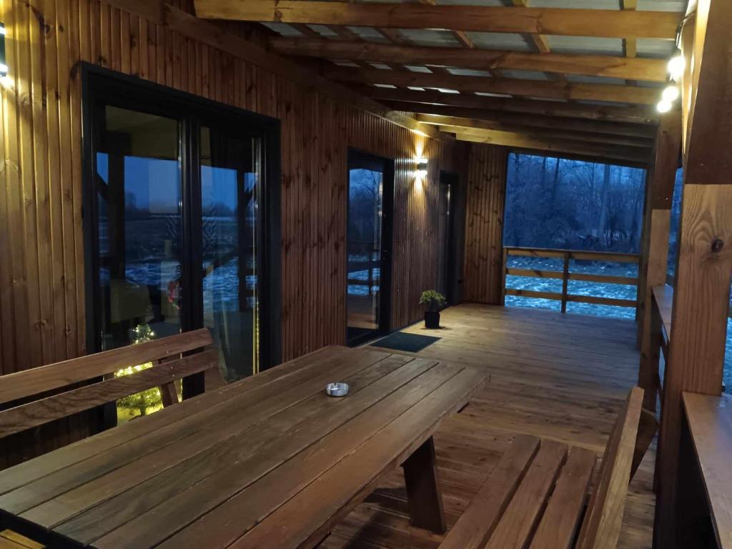 eine hölzerne Veranda mit einem Holztisch auf einer Terrasse in der Unterkunft Raj nad Narwią in Zatory