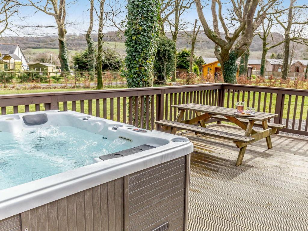 a hot tub on a deck with a picnic table at 3 Bed in Dartmoor National Park 06199 in Okehampton