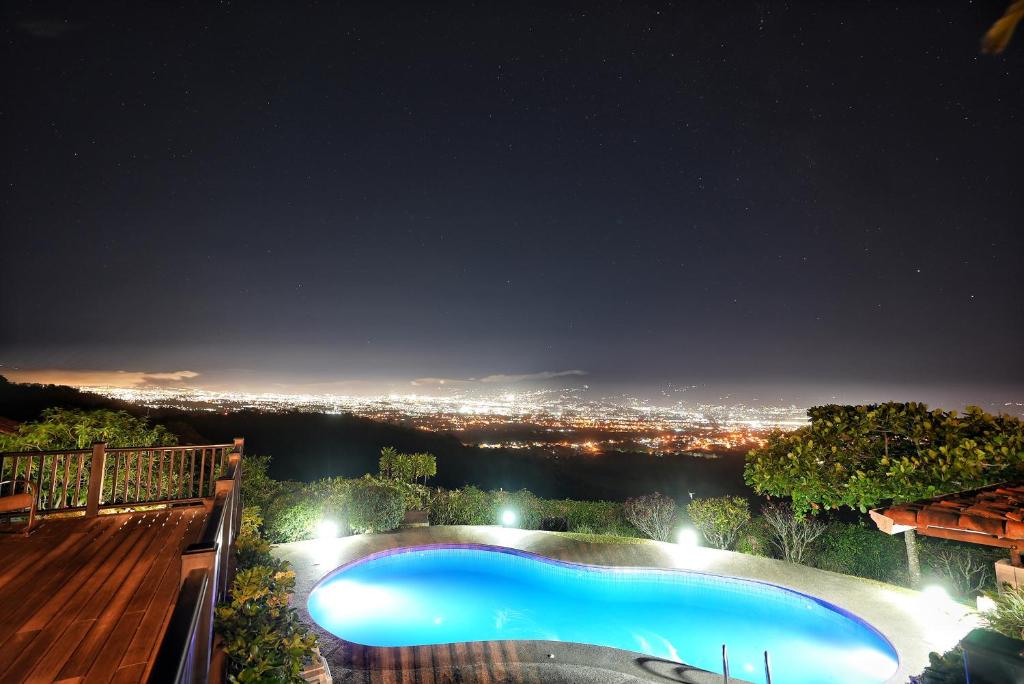 uma piscina à noite com vista para a cidade em Villas Aracari em Alajuela