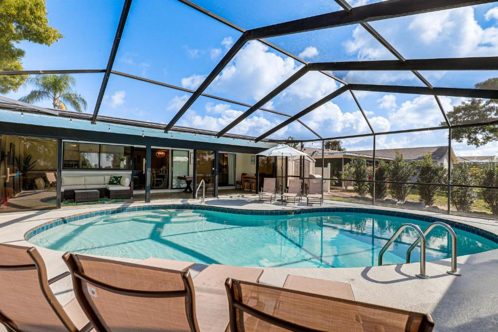 una piscina con sedie e tetto in vetro di Apollo Beach Oasis Lanai and Heated Pool! a Apollo Beach
