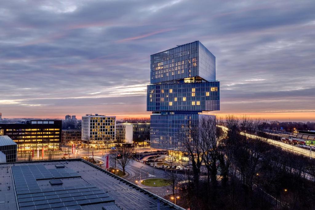 um edifício de vidro alto em uma cidade à noite em nhow Amsterdam Rai em Amsterdã