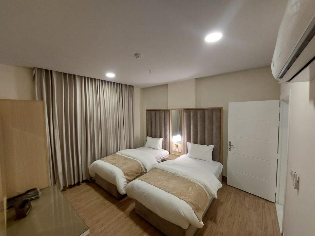 ein Hotelzimmer mit 2 Betten und einem Fenster in der Unterkunft شقق كيان البستان للشقق المخدومة in Al-Hasa