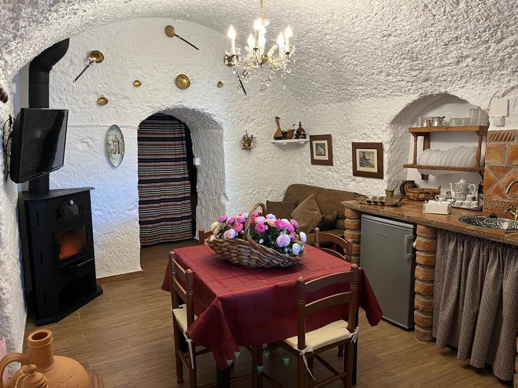 - une cuisine avec une table et un panier de fleurs dans l'établissement la cueva de guadix, à Guadix