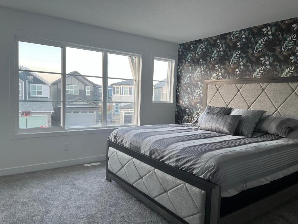 a bedroom with a bed and a large window at Entire4BedroomHomeKingParkingKitchenWasherDryerFastWiFi in Calgary