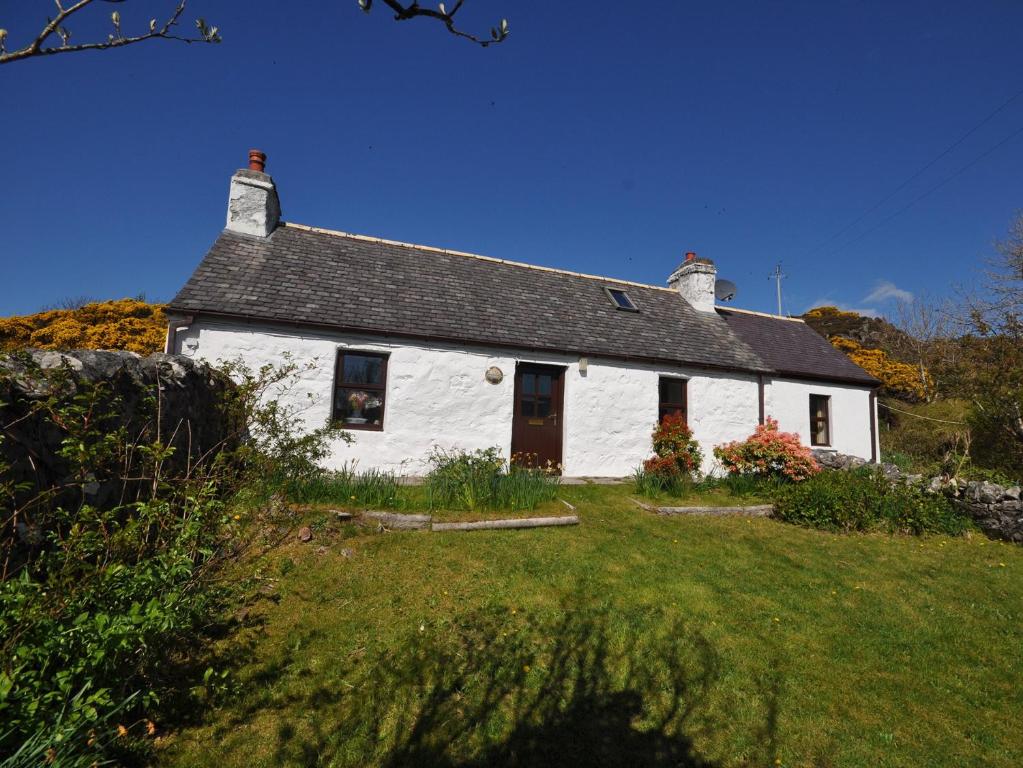 a white house with a grass yard in front of it at 1 bed property in Lochinver The Highlands SU304 in Lochinver