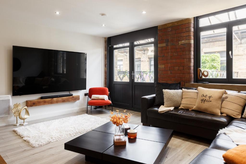 a living room with a couch and a tv at Stylish Penthouse with outside balcony! in Bradford