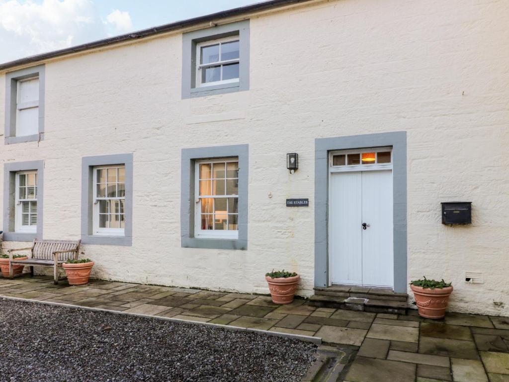 a white house with a white door and windows at The Stables in Dumfries