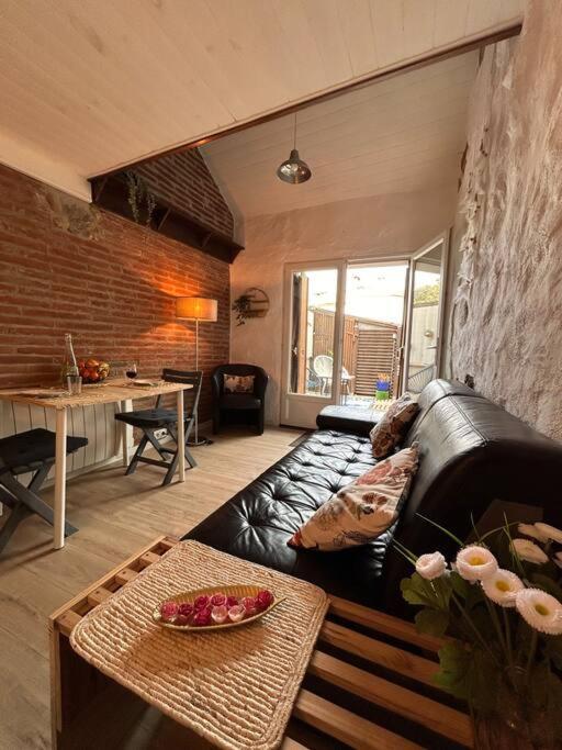 un salon avec un canapé en cuir noir et une table dans l'établissement Charmant duplex 2 chambres/terrasse, à Prades