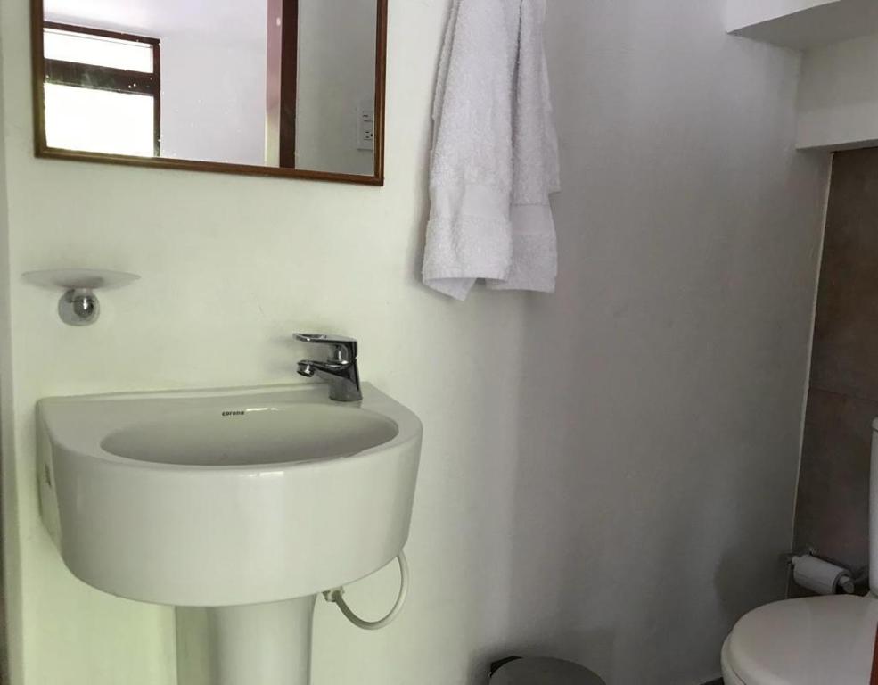 a bathroom with a sink and a mirror and a toilet at Cabañas Don Rafa Santa Marta in Santa Marta