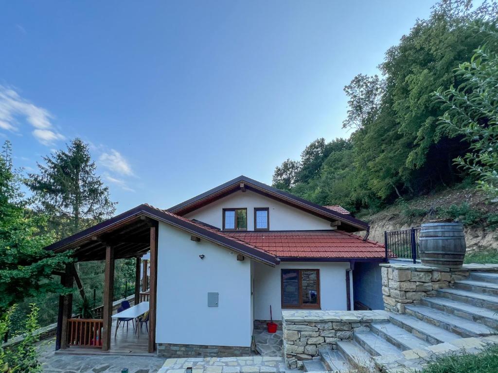 a small white house with a porch and stairs at Villa Ksilifor in Veliko Tŭrnovo