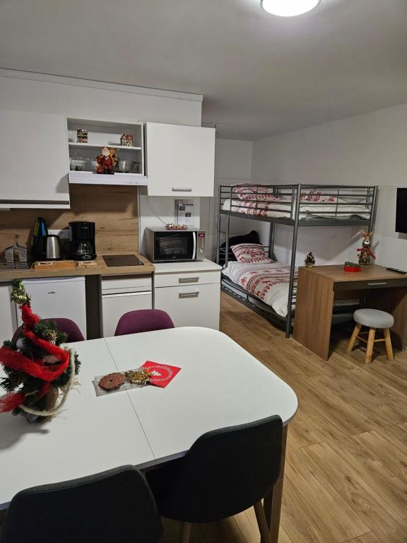 a kitchen and living room with a table and a bunk bed at Studio Le Tétras Résidence de tourisme in La Féclaz