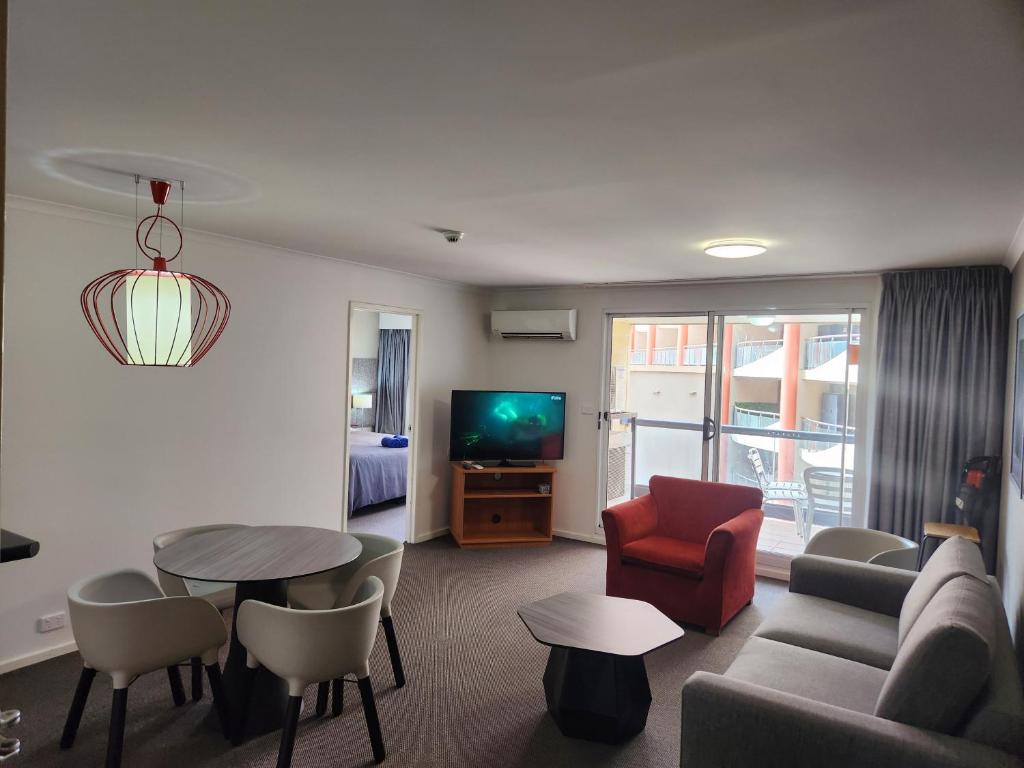 a living room with a couch and a table and a tv at Canberra City Accommodation in Canberra