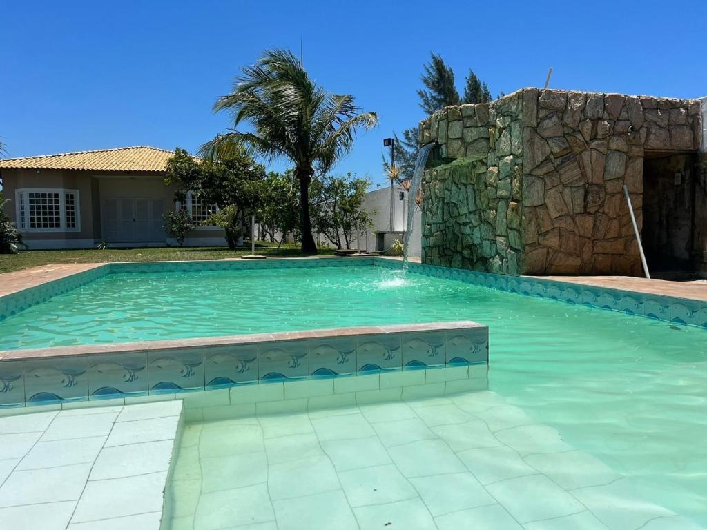 a swimming pool in a house with a stone wall at Casa de Praia Com Piscina perto da praia in São João da Barra