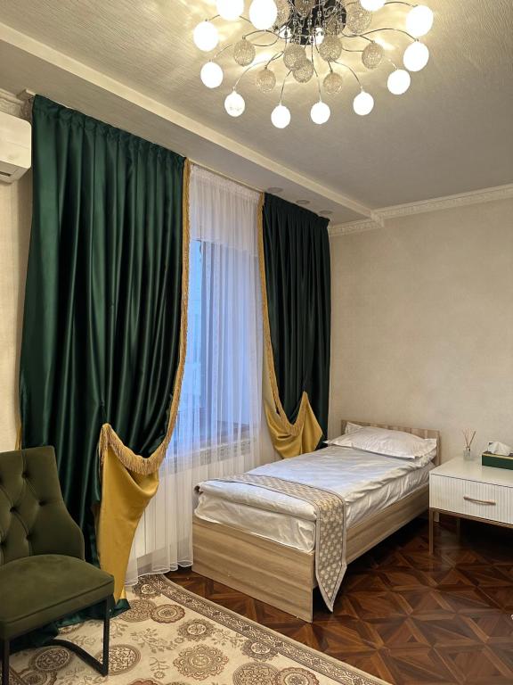 a bedroom with a bed and a green curtain at Sultan Saray in Osh