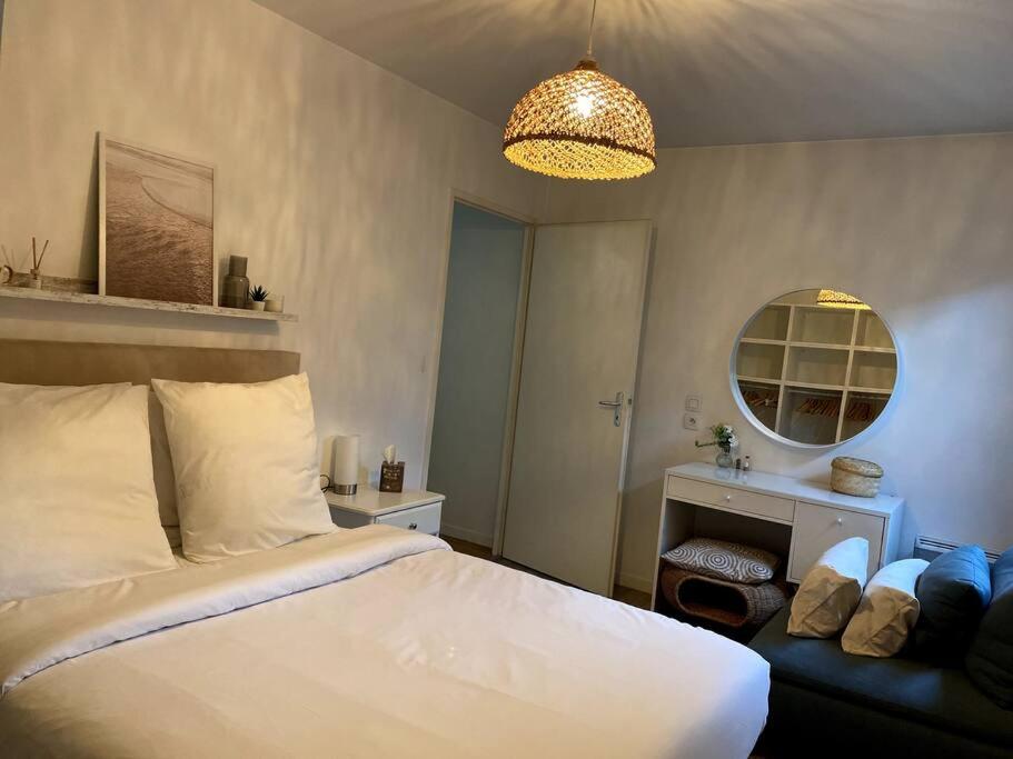a bedroom with a white bed and a chandelier at Charming Flat with Easy Access to Paris in Valenton