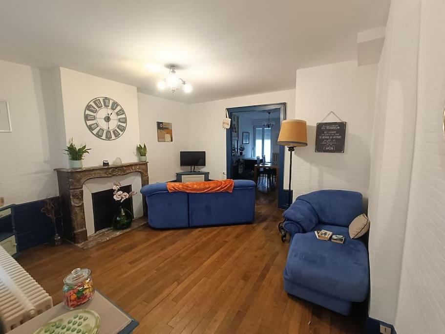 a living room with a blue couch and a fireplace at Appartement au charme authentique in Mirecourt