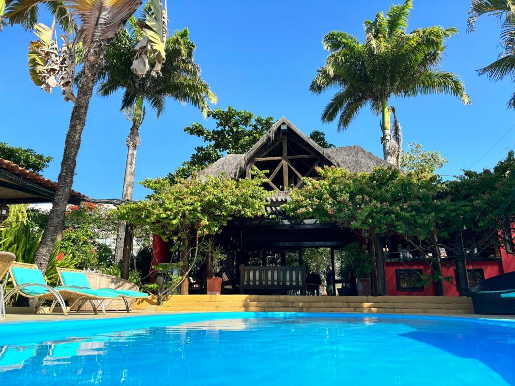 una piscina frente a un complejo con palmeras en Hotel Aconchego Porto de Galinhas, en Porto de Galinhas