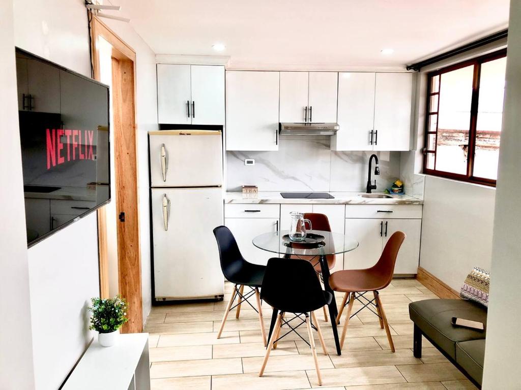 uma cozinha com armários brancos e uma mesa e cadeiras em Family Apartment centro ciudad + Netflix em Cuenca
