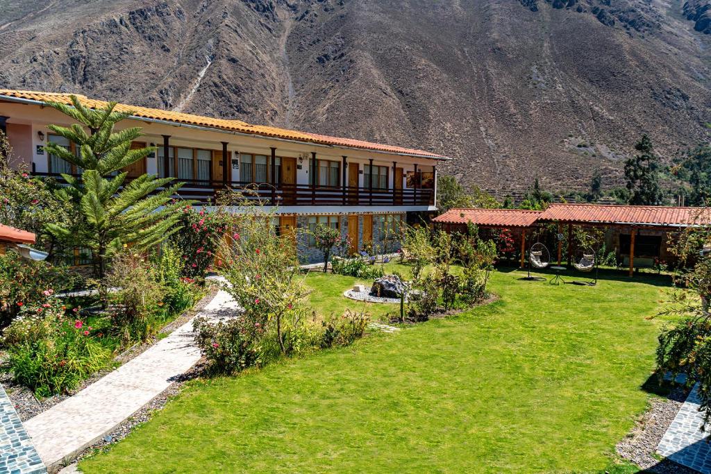 a house with a garden in front of a mountain at Hotel Tierra Inka Sacred Valley in Ollantaytambo