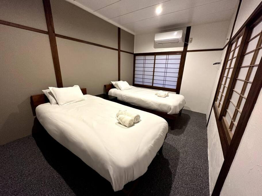 a hotel room with two beds and a window at AOBA Hakuba self-contained home in Hakuba
