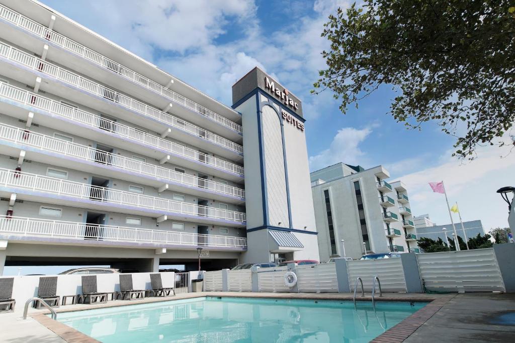 a hotel with a swimming pool in front of a building at Marjac Suites Virginia Beach Oceanfront in Virginia Beach