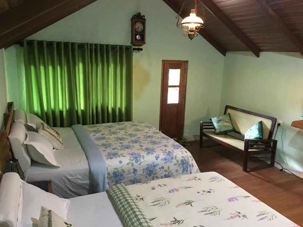 two beds in a room with green curtains at The Vintage Villa - Knuckles in Rangala
