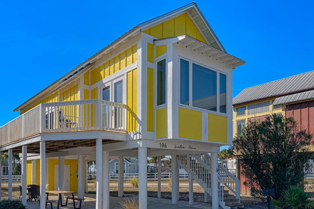 uma casa amarela com um alpendre e um deque em Sunshine Haven em Carrabelle