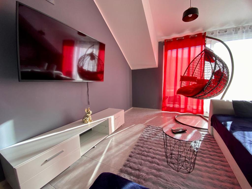 a living room with a large tv and red curtains at Banićević APARTMANI in Đenovići