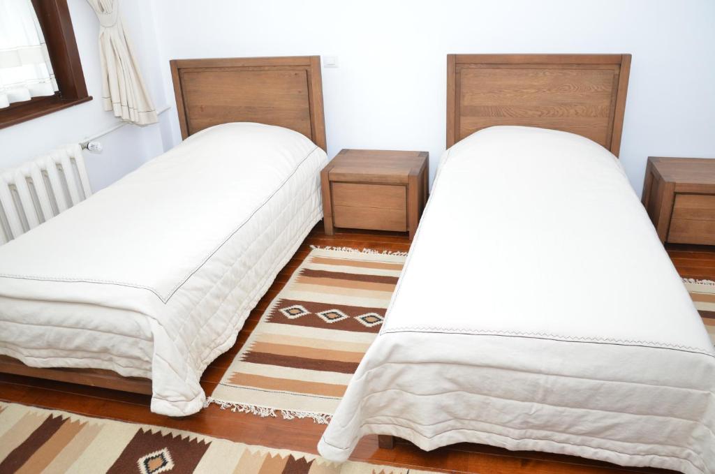 two beds in a room with white sheets at Casa de Oaspeți Sfântul Nicolae in Iaşi