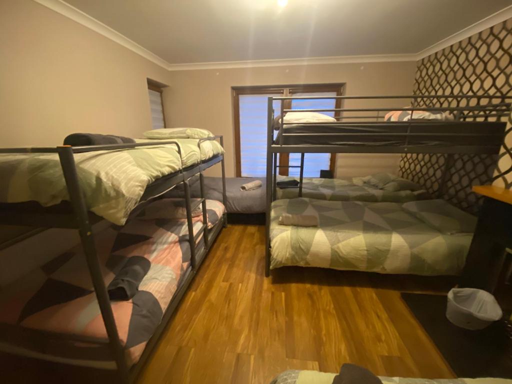 two bunk beds in a room with wooden floors at Dublin Airport Big rooms with bathroom outside room - kitchen only 7 days reservation in Dublin