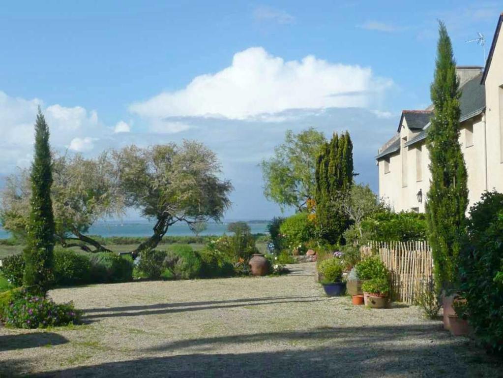 een tuin met bomen en een huis en een hek bij Fenetres sur le golfe in Sarzeau
