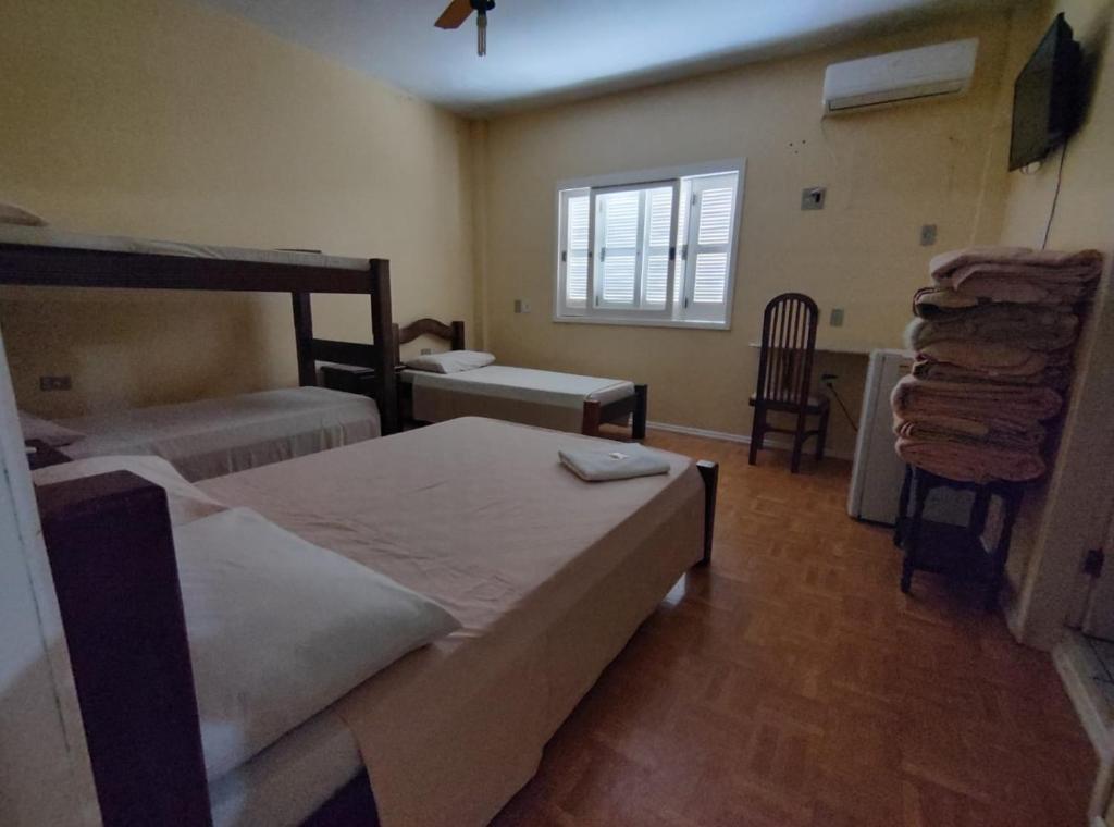 1 dormitorio con 2 camas, ventana y silla en HOTEL BATOVI en São Gabriel