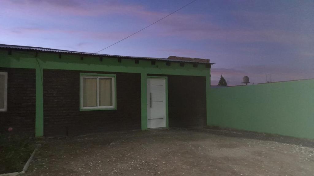 a green and black house with a white door at Mi sueño in San Antonio Oeste